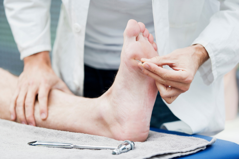 Doctor testing sensibility of foot